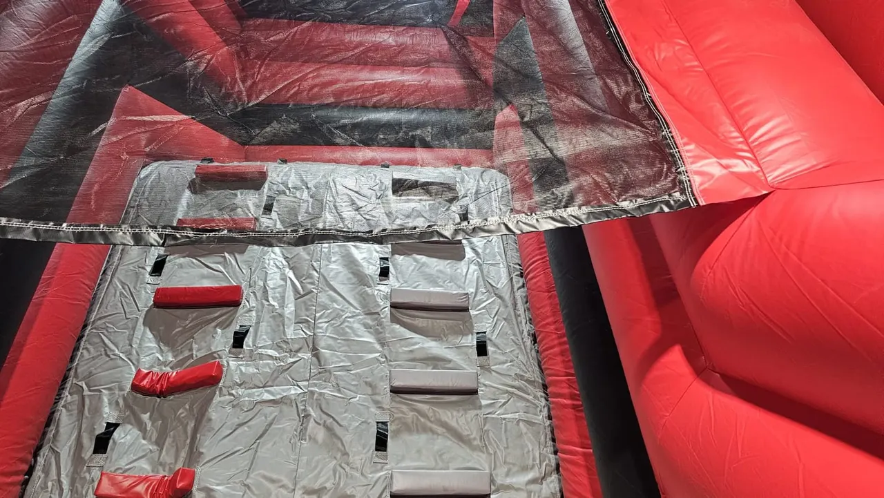 Overhead view of a red and black inflatable bounce house with hand and foothold features.