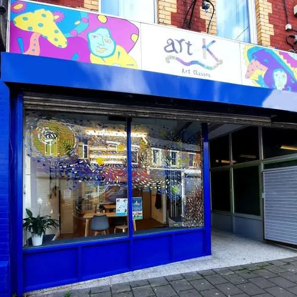Bright blue storefront of an art classes venue with colourful painted signage and window displays showing artwork and studio space.