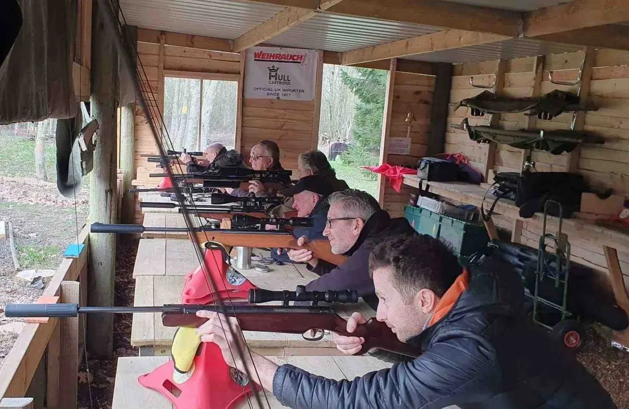 Several people aiming rifles at targets in a wooden shooting range facility.