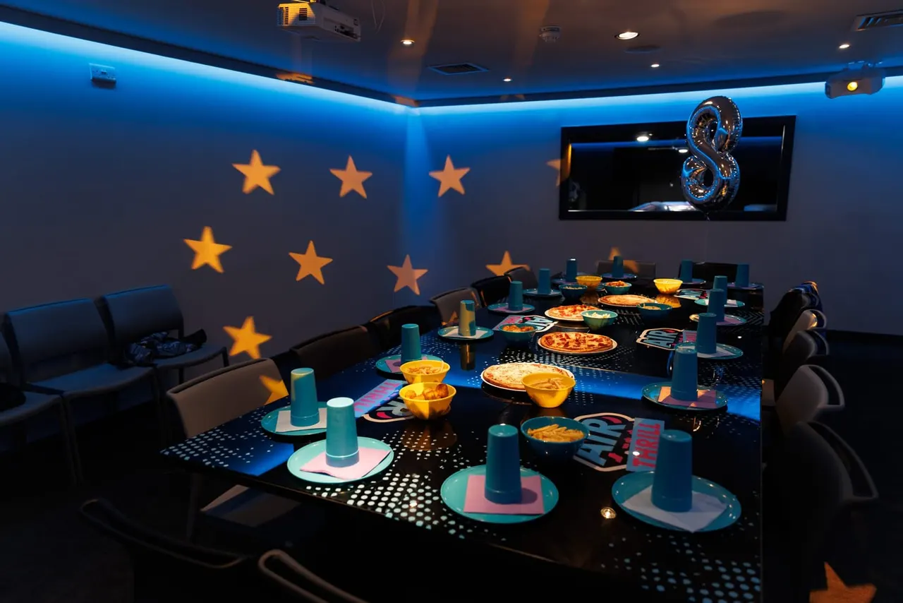 Private dining room with themed table settings, pizzas, and golden stars on blue walls.