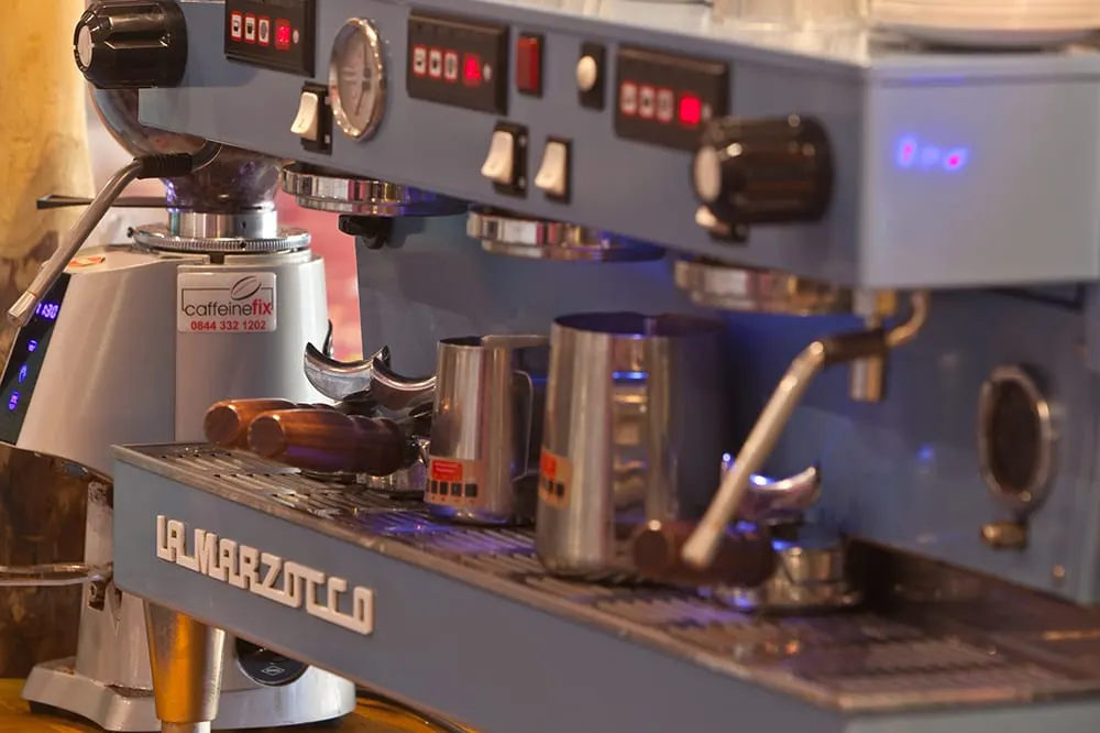 Professional espresso machine with multiple group heads and steam wands at a café counter.