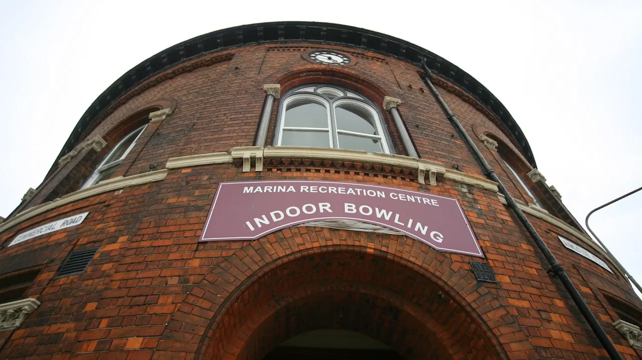 Victorian red brick building with a curved dome roof and arched entrance, displaying a sign for Indoor Bowling.