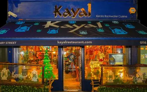 Kayal restaurant storefront illuminated at night with Christmas decorations visible in windows.