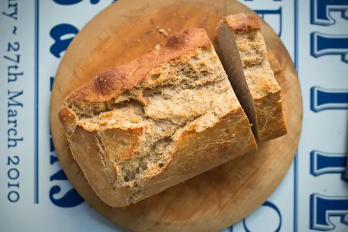 Sliced crusty bread loaf on a wooden board.