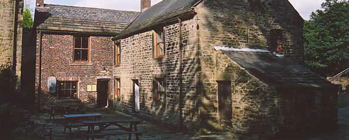 Stone and brick buildings with ivy-covered walls surrounding a courtyard with a picnic table.