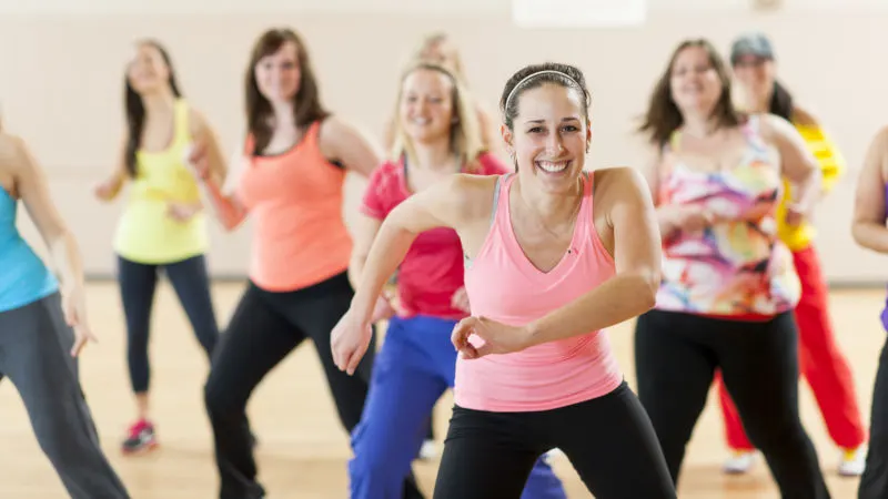 Group of women in colourful sportswear participating in a fitness or dance class indoors.