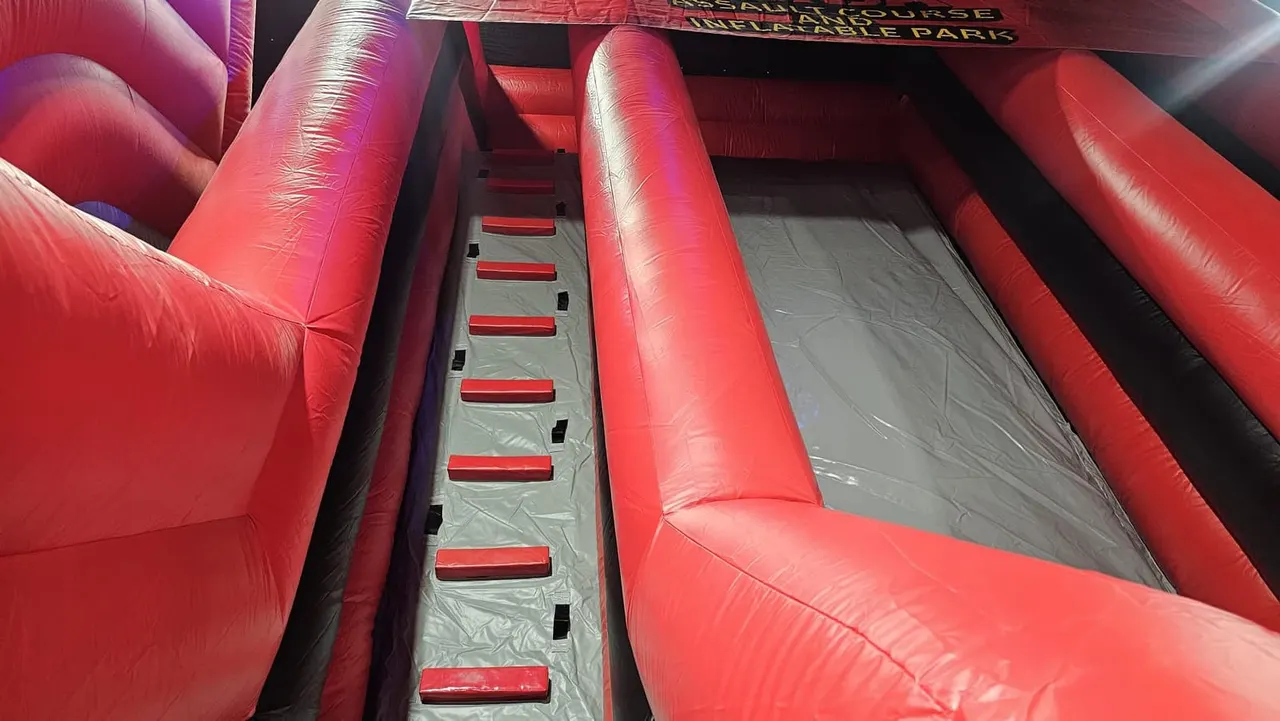 Interior view of a red inflatable obstacle course with climbing steps down the centre.