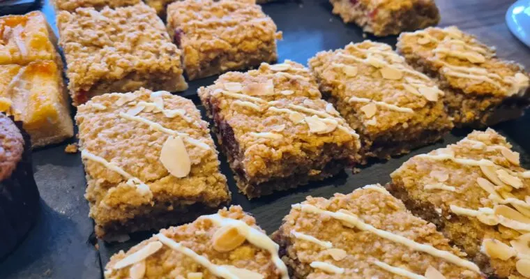 Sliced almond-topped flapjacks or oat bars arranged on a dark surface.