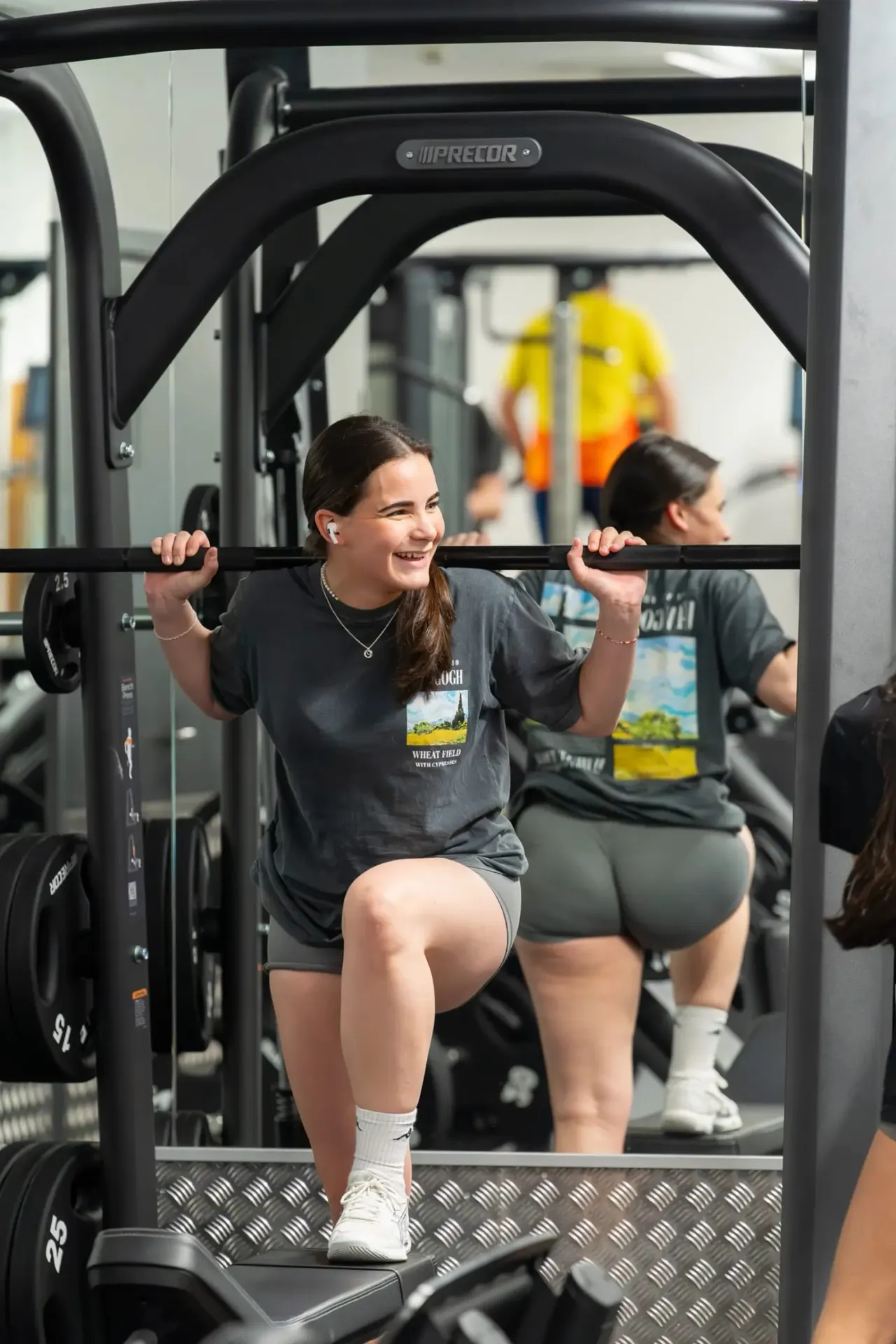 Young woman using a leg press machine in a gym, smiling during her workout.