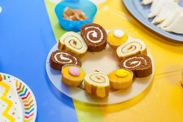 Plate of assorted cakes and cupcakes arranged in a circle at a children's party table.