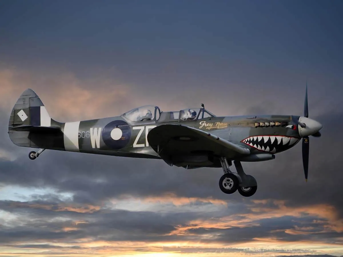 A vintage military aircraft in flight against a dramatic sunset sky.