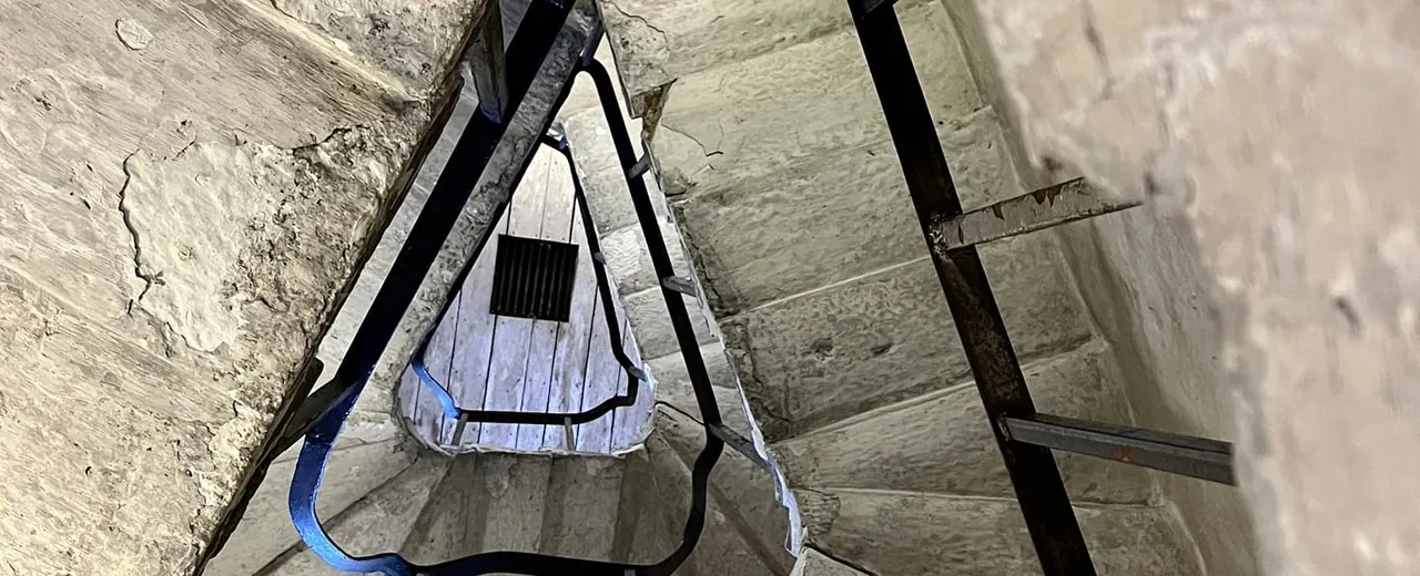 Overhead view of a rowing boat moored between stone walls in an indoor waterway or lock chamber.