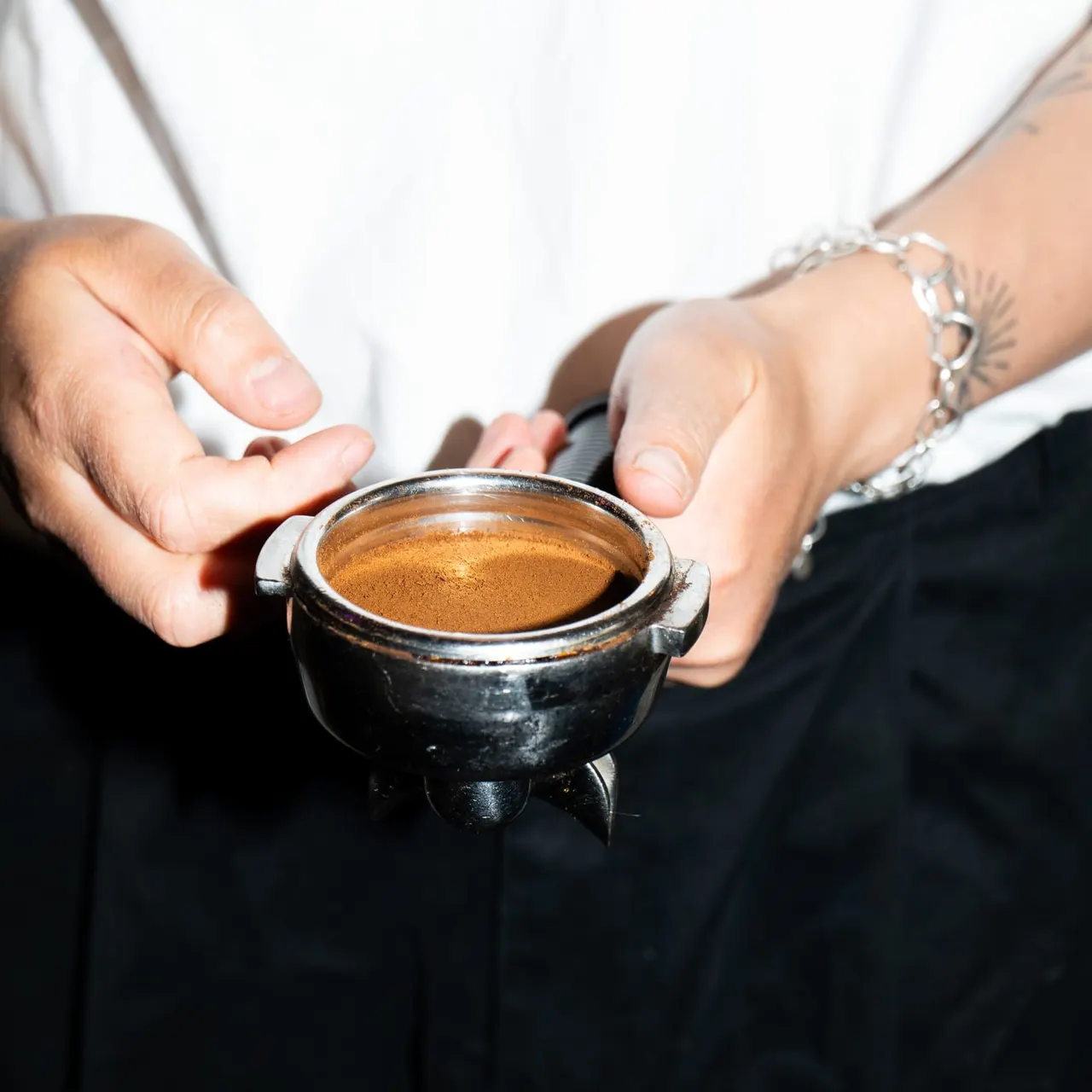 Person holding a small black cauldron filled with brown powder or spice over their palms.