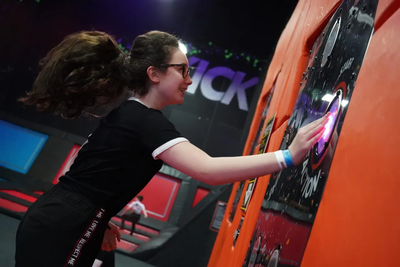Young person playing an arcade racing game machine with colourful illuminated screen.