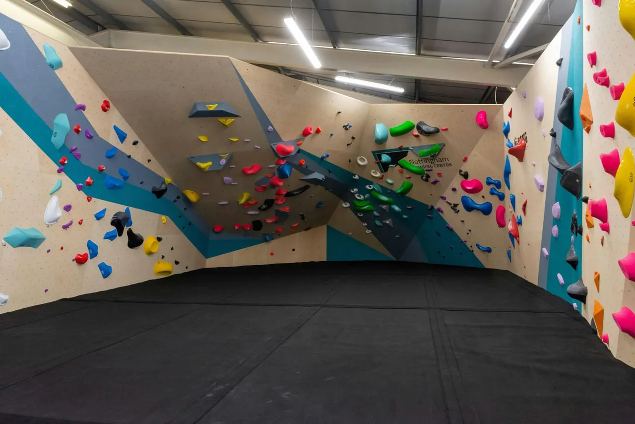 Indoor climbing wall with colourful handholds at an empty climbing centre.