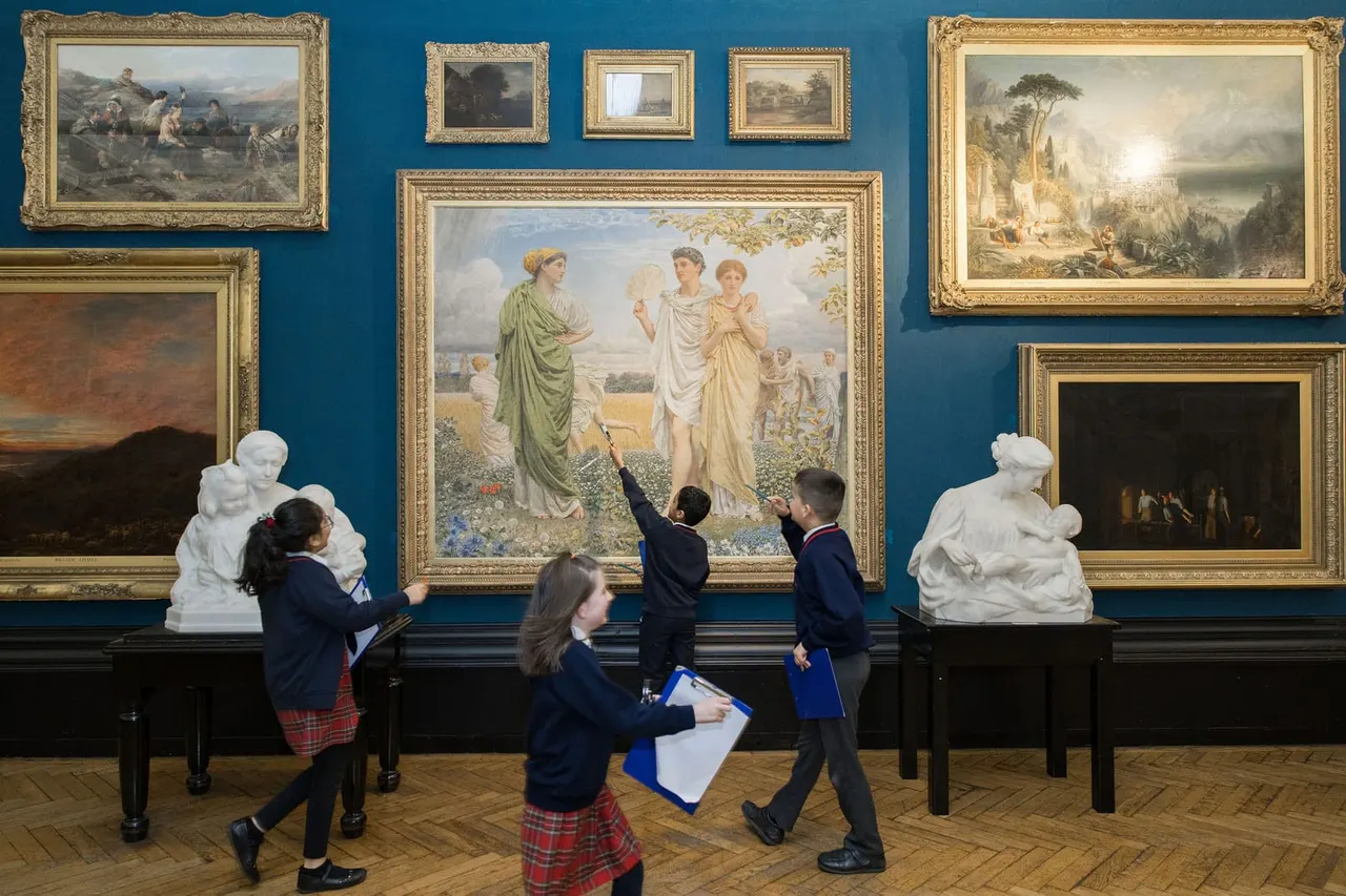 School children on a gallery tour view classical paintings and sculptures displayed on a deep blue wall.