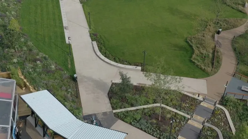 Aerial view of paved pathways winding through landscaped gardens with grass and planted areas.
