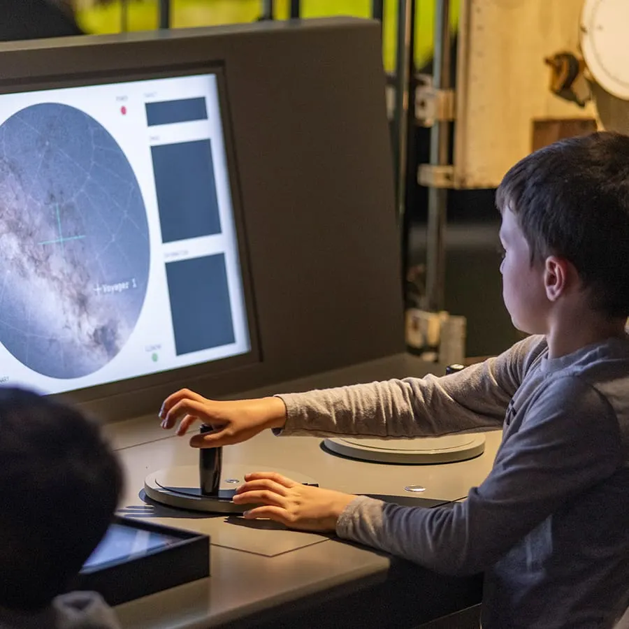 Child using interactive touchscreen display showing moon surface imagery at a planetarium exhibit.