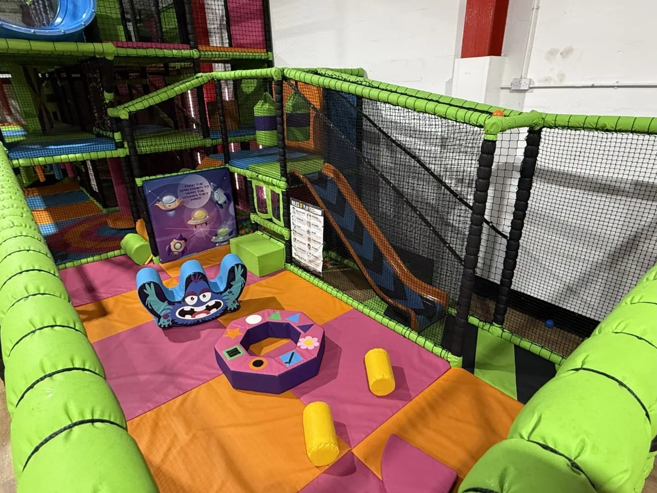 Indoor play structure with colourful padded sections, foam obstacles and mesh-enclosed tunnels for children to climb and jump through.