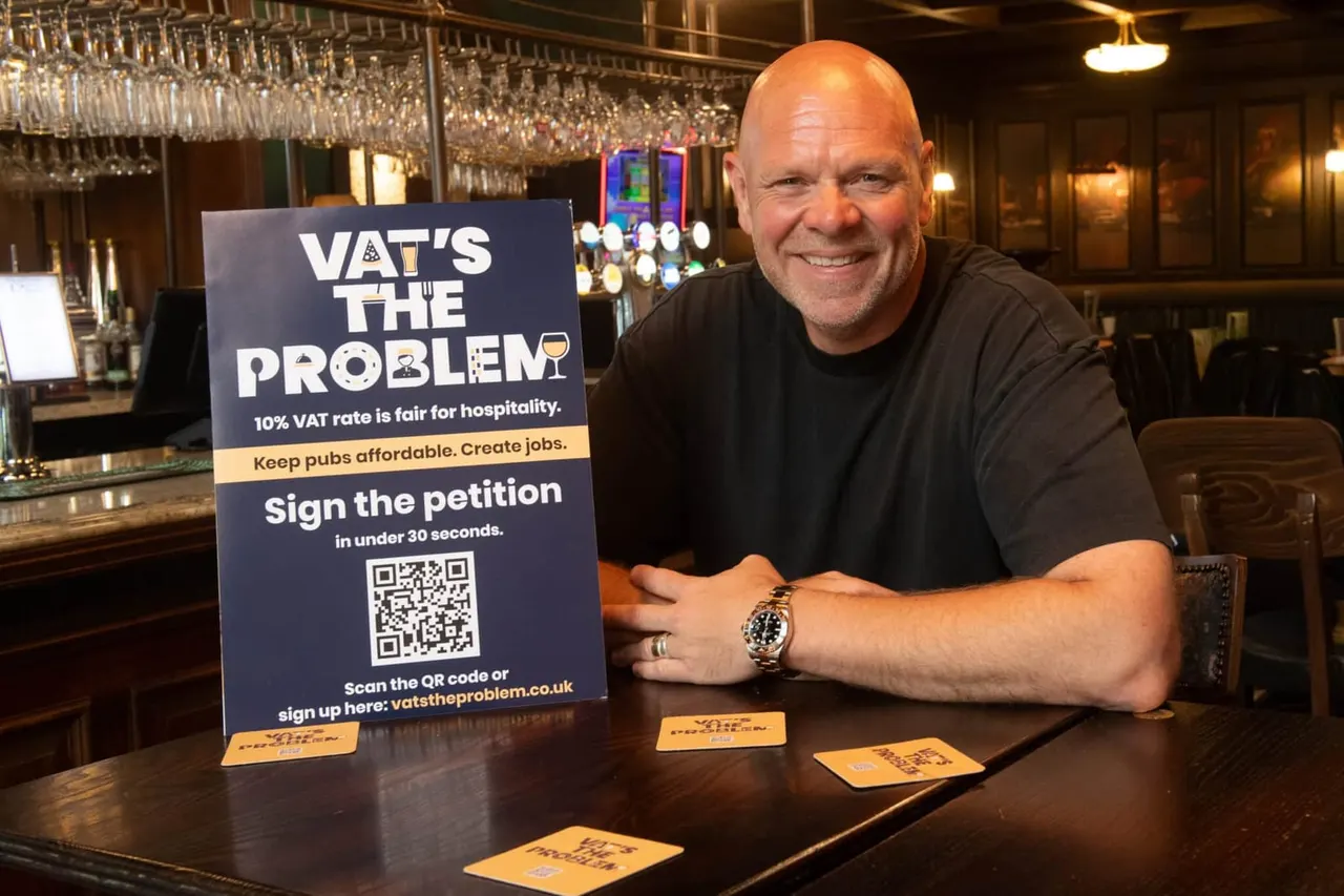 Man smiling at bar counter next to VAT campaign sign with QR code and promotional leaflets.