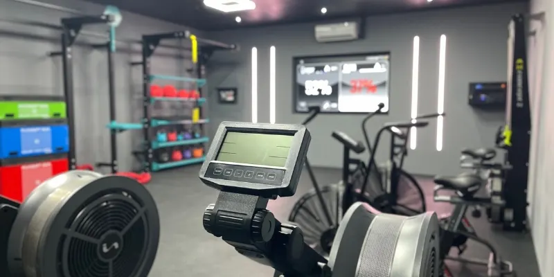 Modern gym interior with rowing machine in foreground and fitness equipment visible throughout the studio.