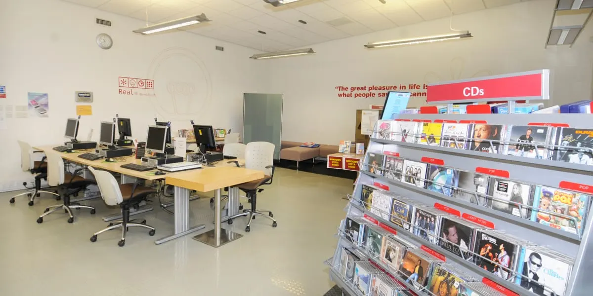 Library interior with computer workstations on left and CD display shelves on right.