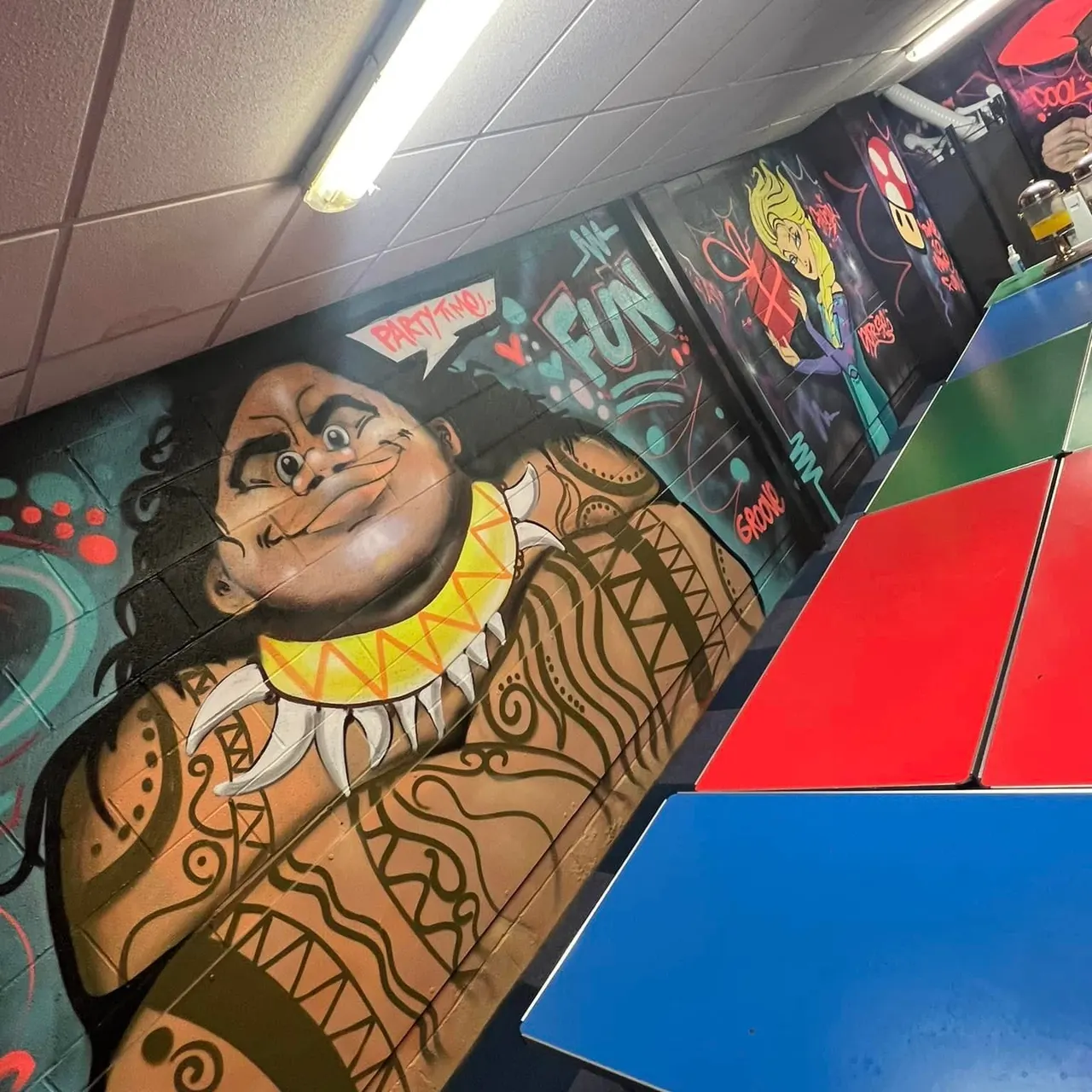 Arcade games and a painted troll character decoration inside an indoor play venue.