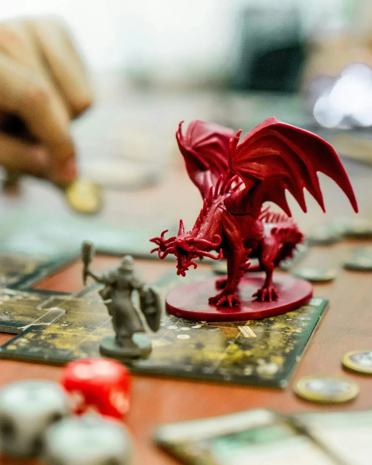 Red dragon figurine positioned on a fantasy board game map with other miniature pieces and tokens.