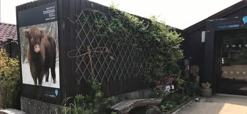 Black structures with ivy and plants growing around them, featuring signage with a large animal image on the side wall.
