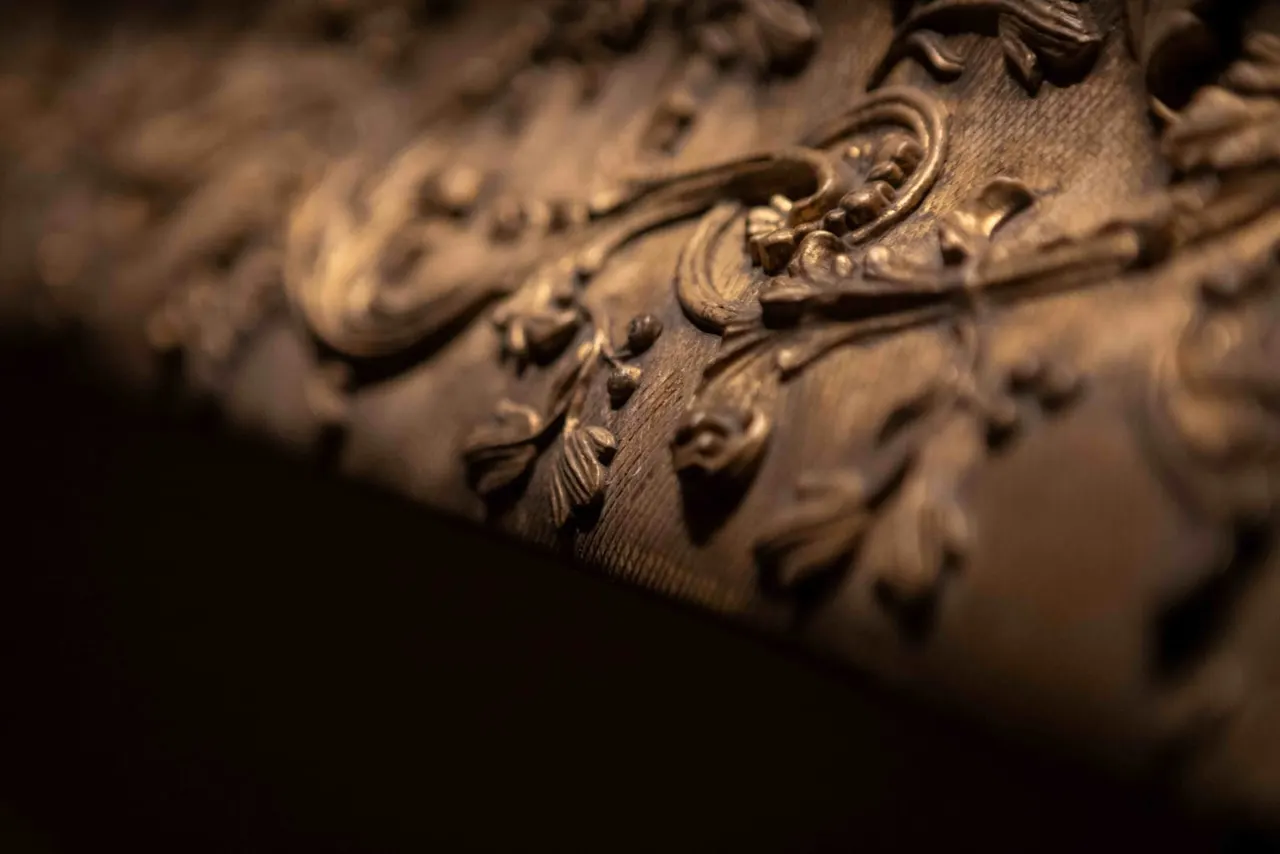 Close-up of ornate carved architectural detail with scrolled acanthus leaf motifs in stone or plaster.