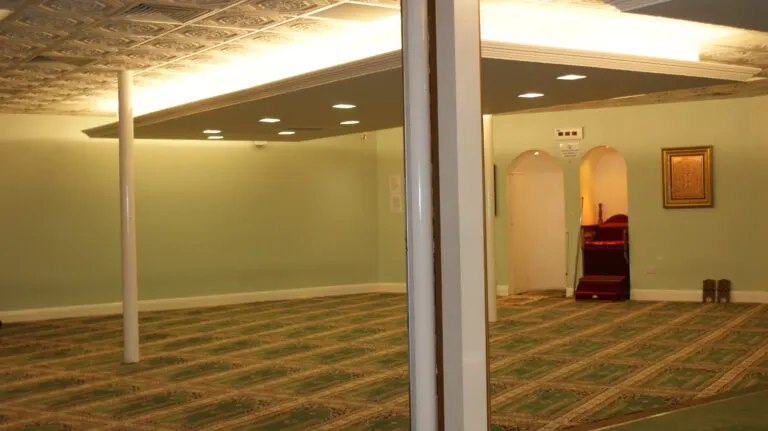 Empty function room with pale green walls, patterned carpet and supporting columns.