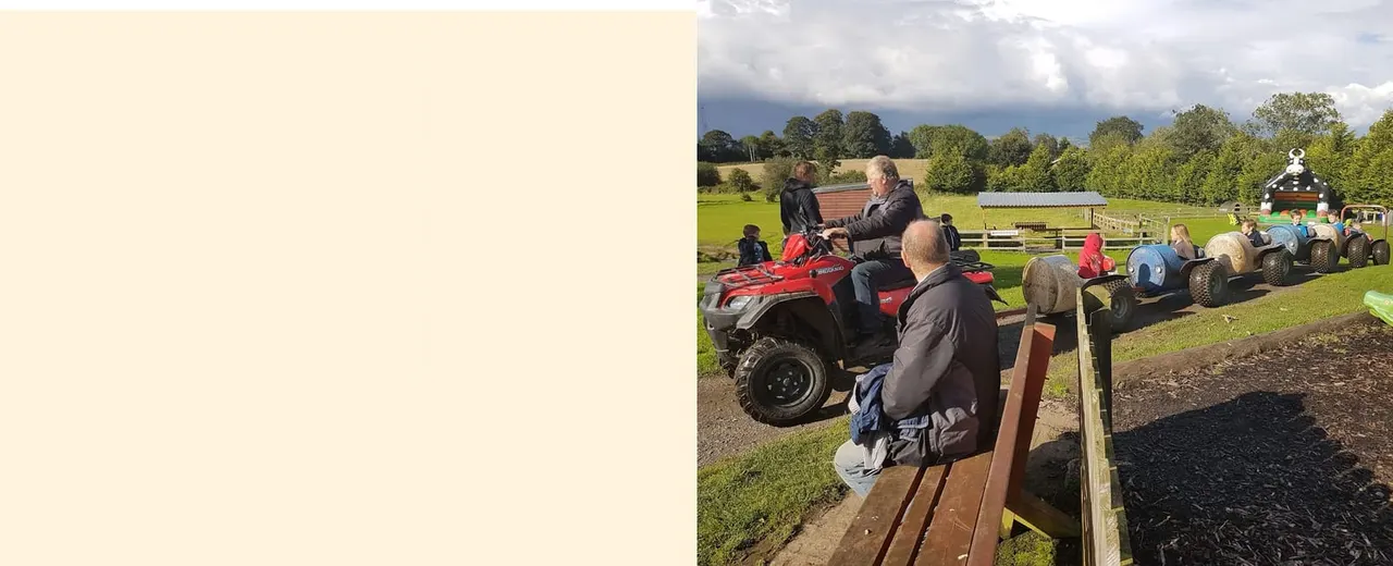 Adults and children riding quad bikes and off-road vehicles in a rural activity park setting.