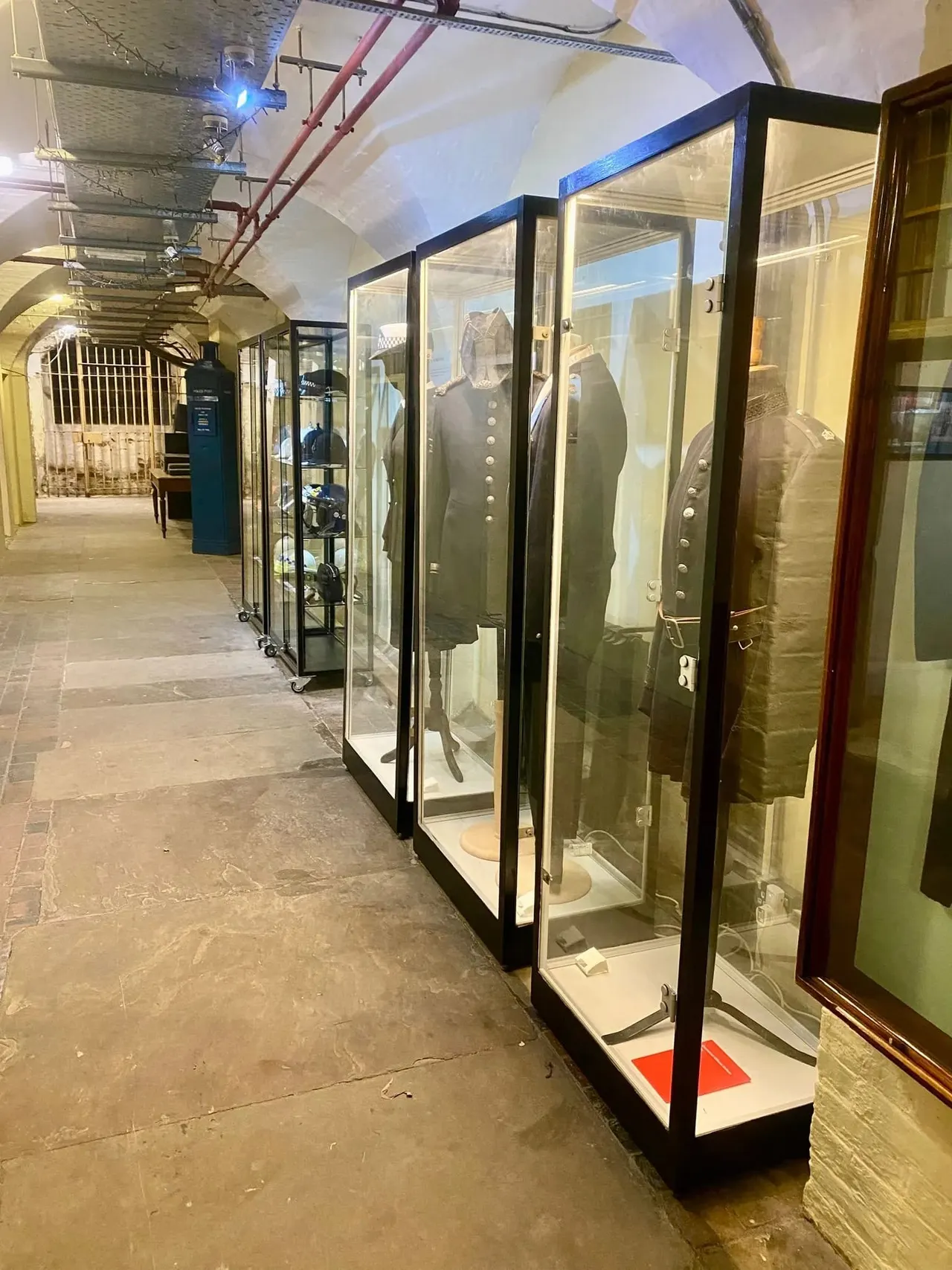 Museum corridor displaying historic military uniforms and artefacts in glass display cases.