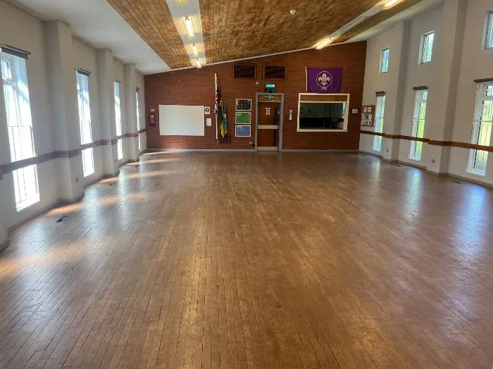 Empty wooden-floored hall with mirrors and wooden wall panelling, suitable for group activities.