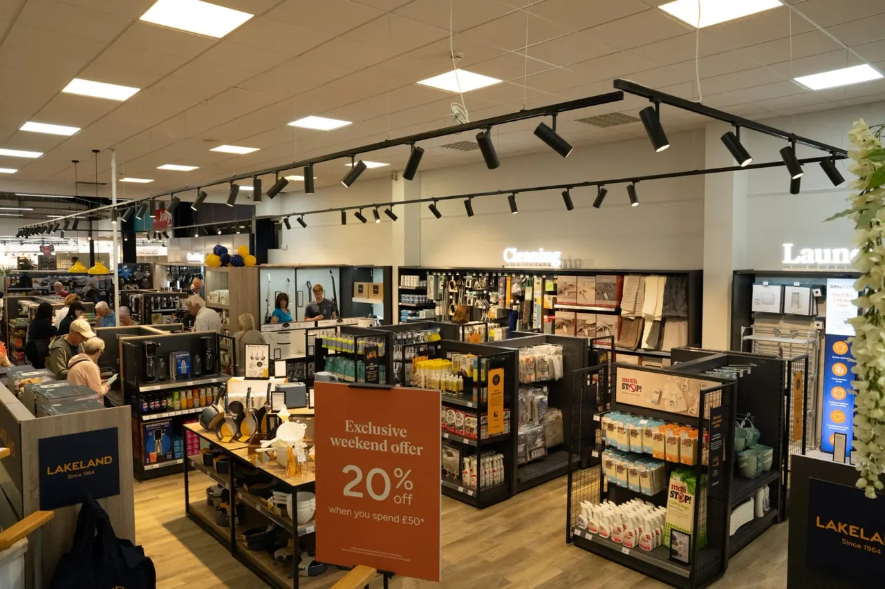 Interior of a retail shop with customers browsing merchandise displays, checkout counters and promotional signage.