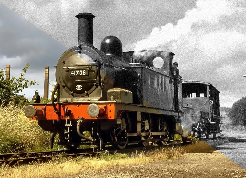 Restored steam locomotive number 41708 with orange and brass livery, emitting steam, stationary on railway tracks.