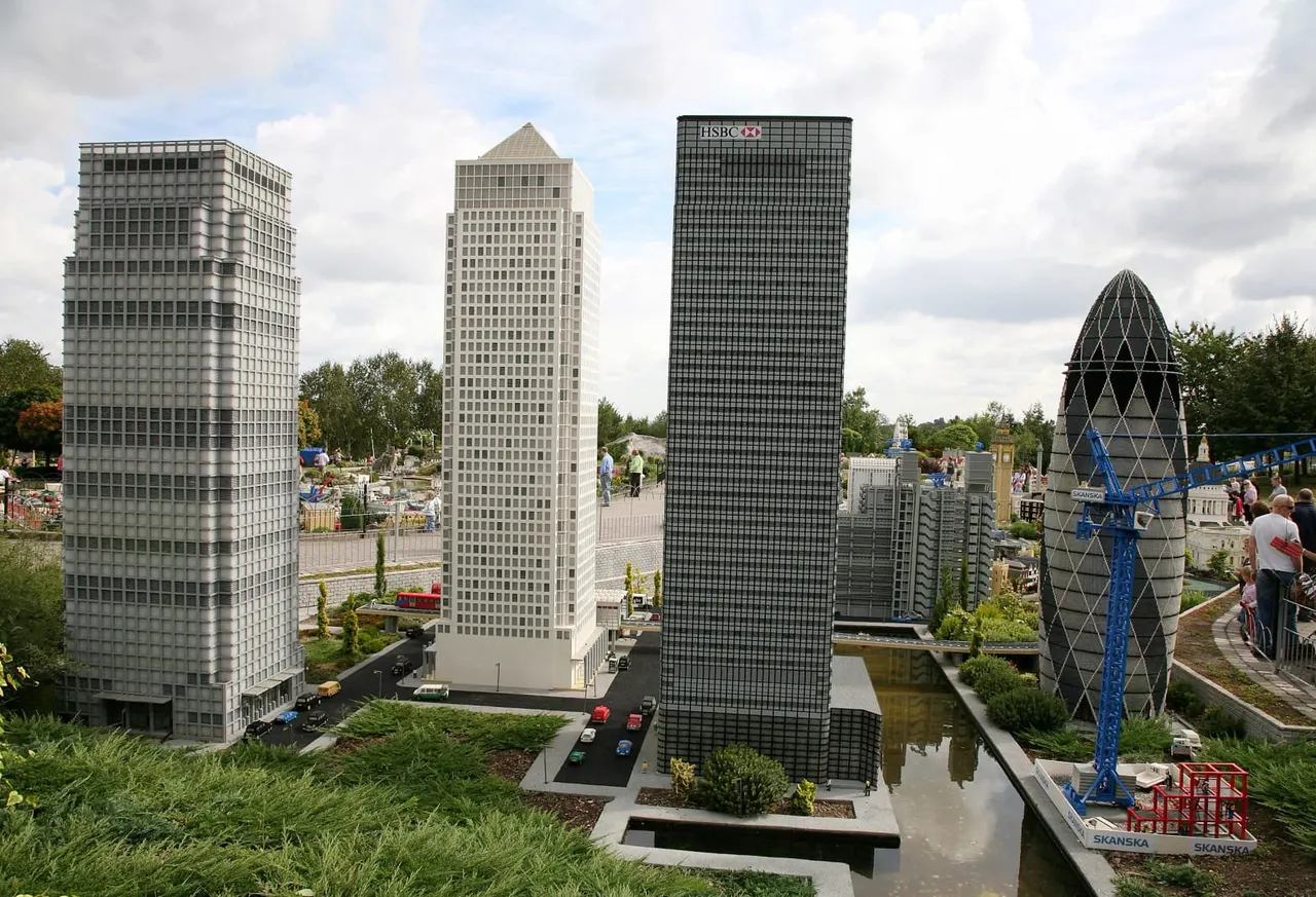 Miniature model buildings including skyscrapers and a distinctive egg-shaped structure, with visitors walking around the miniature cityscape display.