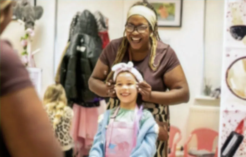 An adult and young child doing a hair or beauty activity together in an indoor salon or spa setting.