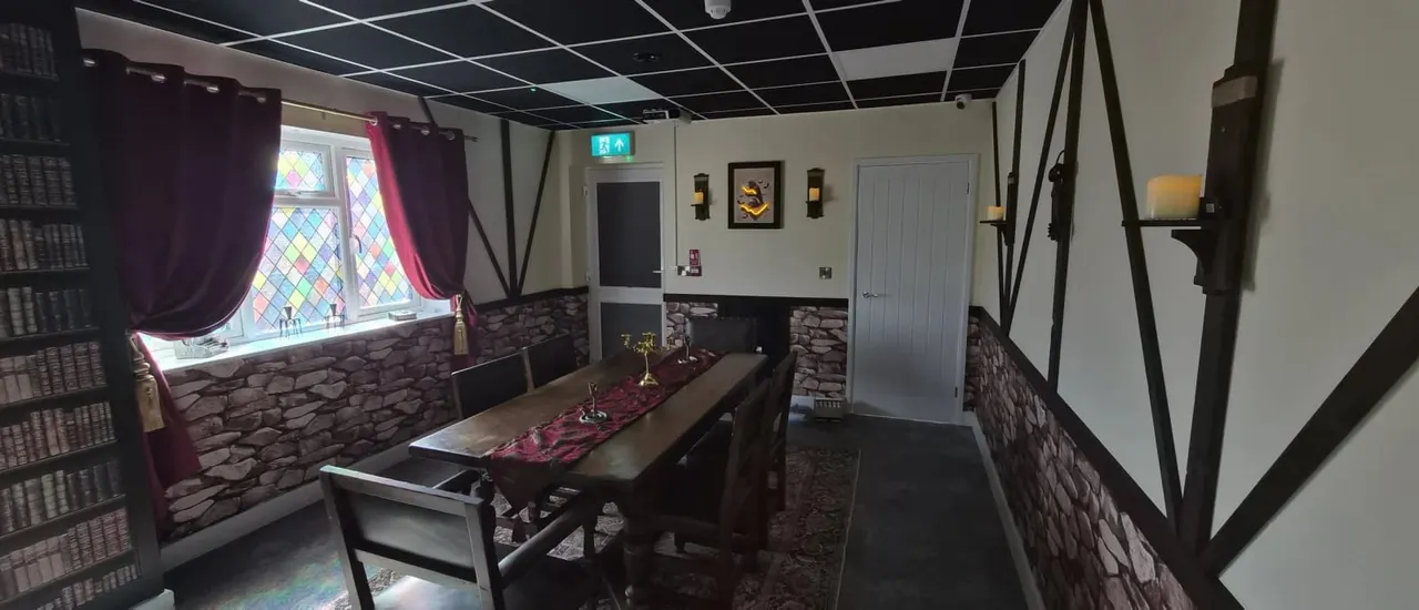 Medieval-themed indoor games room with pool table, stone walls, burgundy curtains and Tudor-style beams.