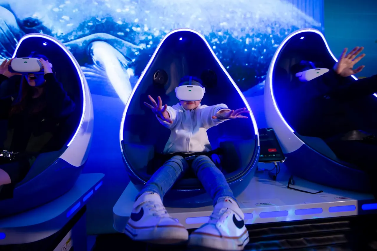 Visitors wearing virtual reality headsets experience an underwater-themed VR simulation with neon-lit pod seating and projected marine life imagery.