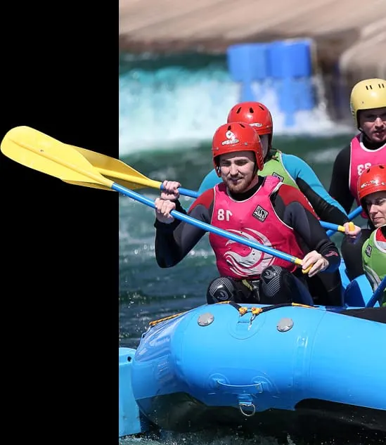 Group of people white water rafting in a blue inflatable boat with paddles on a white water course.