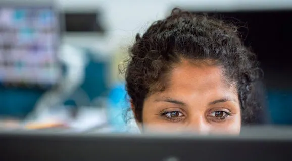 Woman looking over a desk or counter in an indoor venue setting.