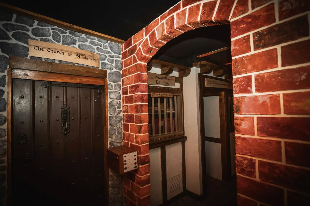 Historic stone and brick building facade with wooden doors at night, featuring a Church of St Gabriel sign.