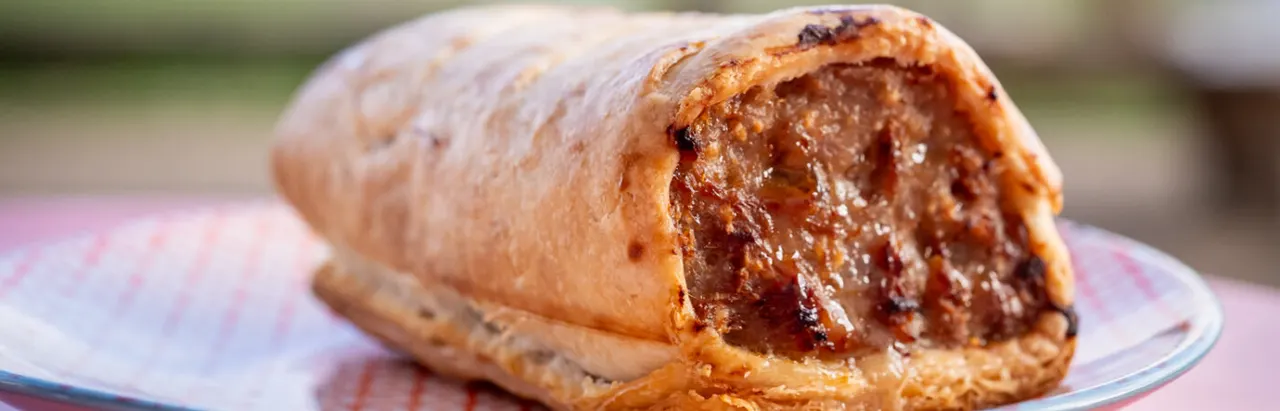 A pastry with a dark jam or fruit filling cut open on a plate.
