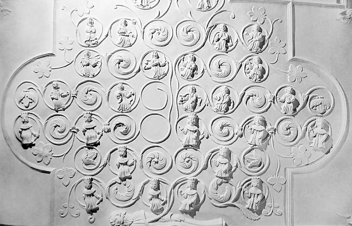 Decorative plasterwork featuring circular medallions with relief figures and ornamental scrollwork in a symmetrical arrangement.
