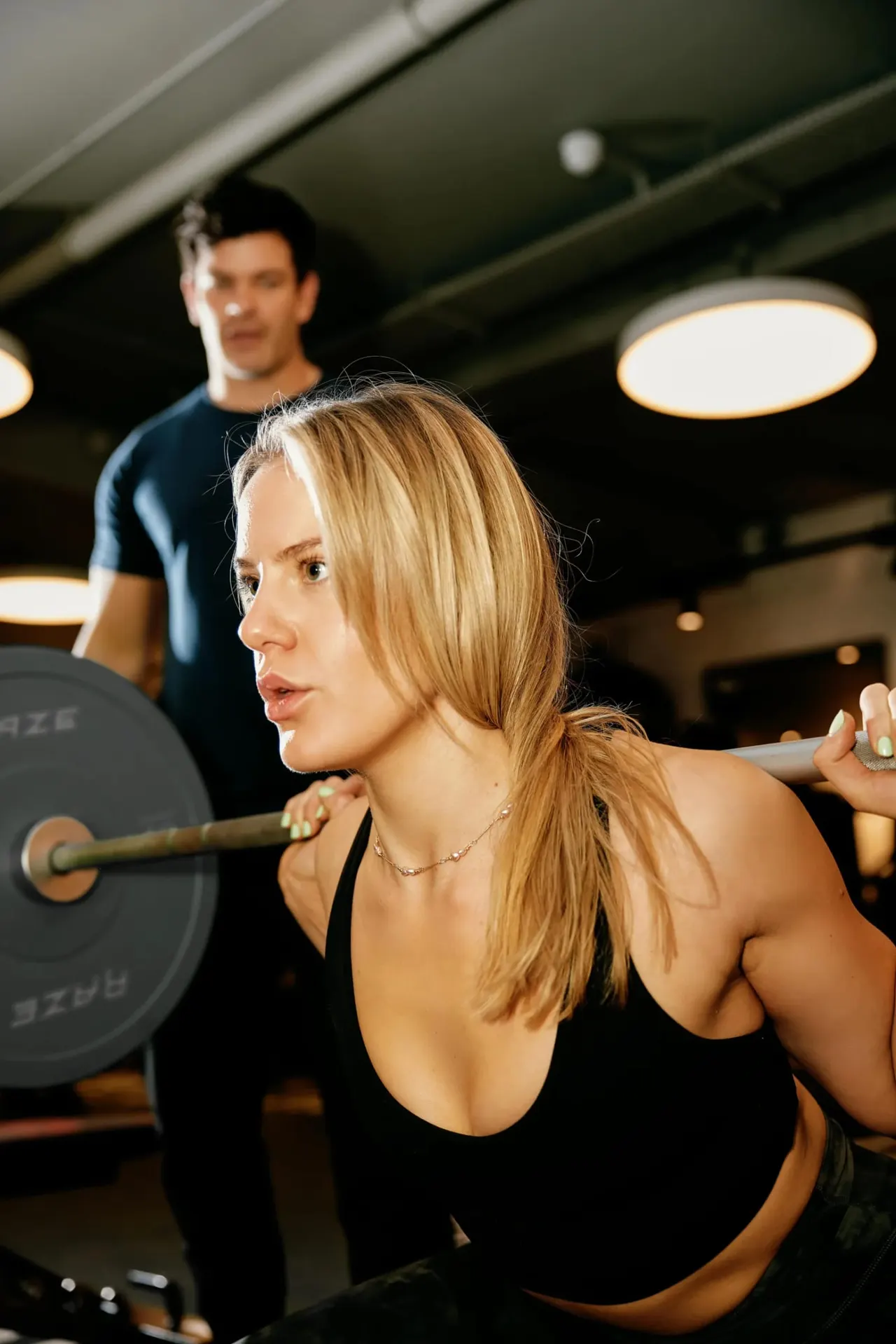 Woman lifting a barbell during a strength training workout in a modern gym facility.