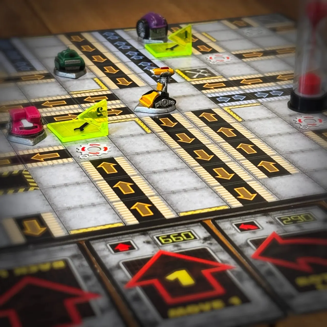 Robot-themed board game in progress with coloured game pieces and cards on an industrial-style grid board.