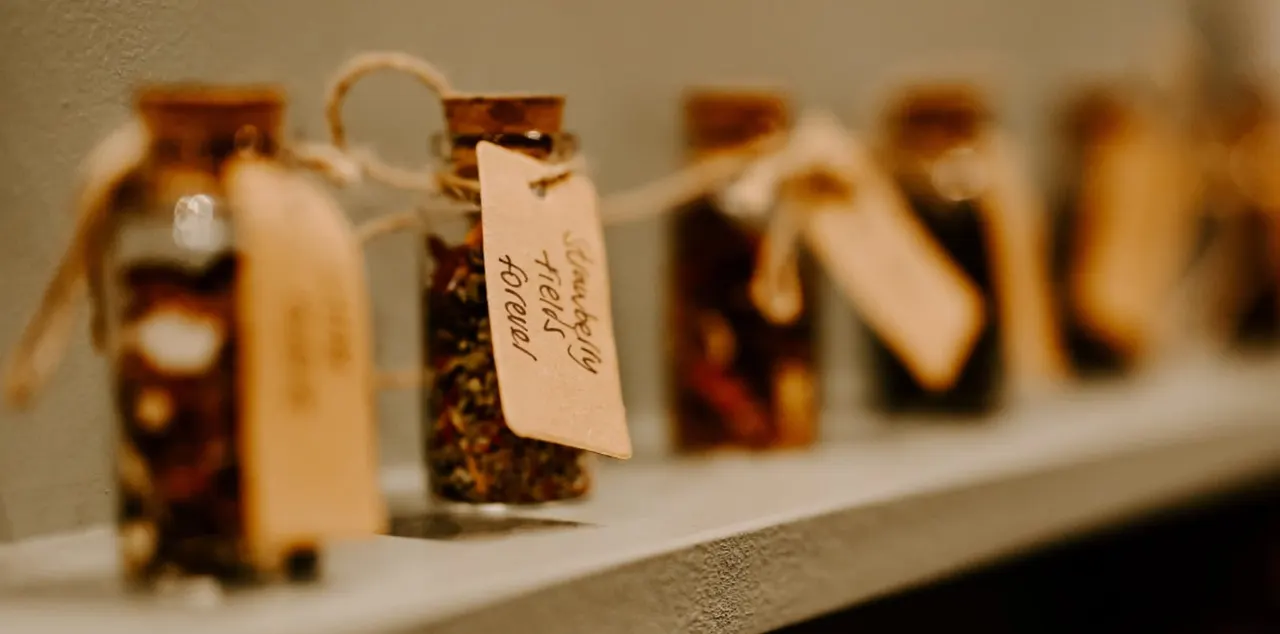 Row of labelled jars containing loose tea blends displayed on a shelf.