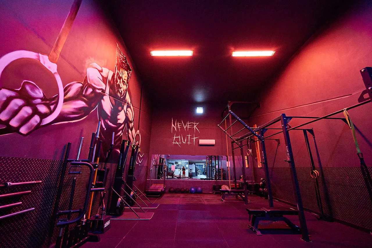 Modern gym interior with neon pink and red lighting, exercise equipment, and motivational wall art.