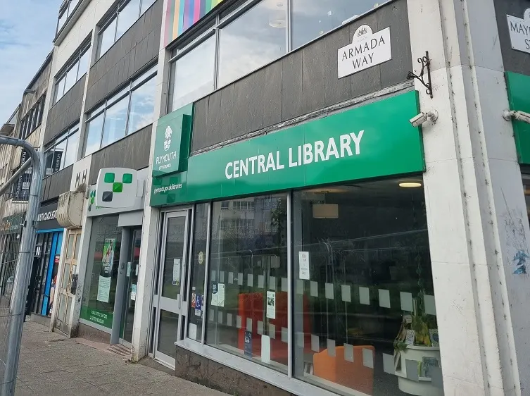 This is a photograph, not a designed graphic.

Exterior of a modern Central Library building with a green awning and storefront on a town street.